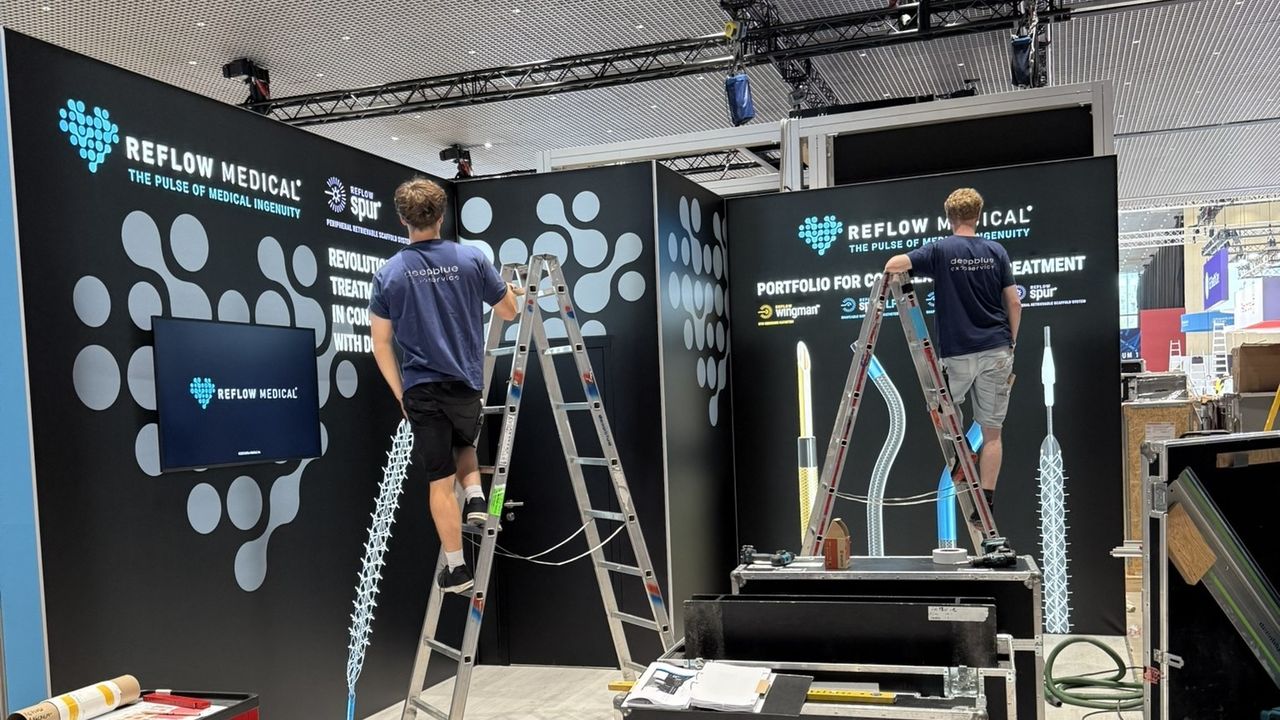 Two deepblue-exposervice technicians on ladders building an exhibition stand for Reflow Medical